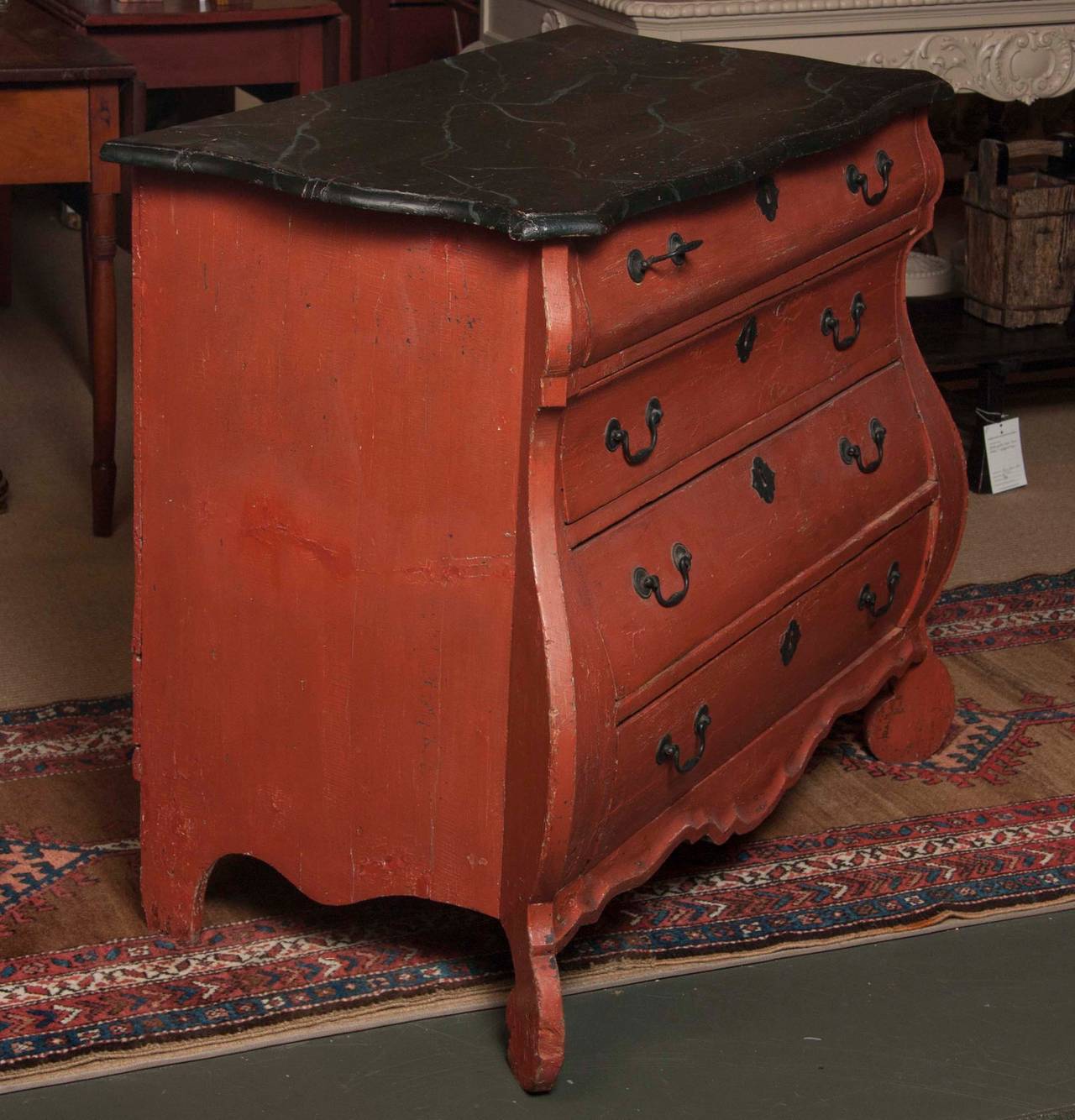 An early period Continental brick and faux-marble painted pine bombe-form commode or chest of drawers.  Restorations.