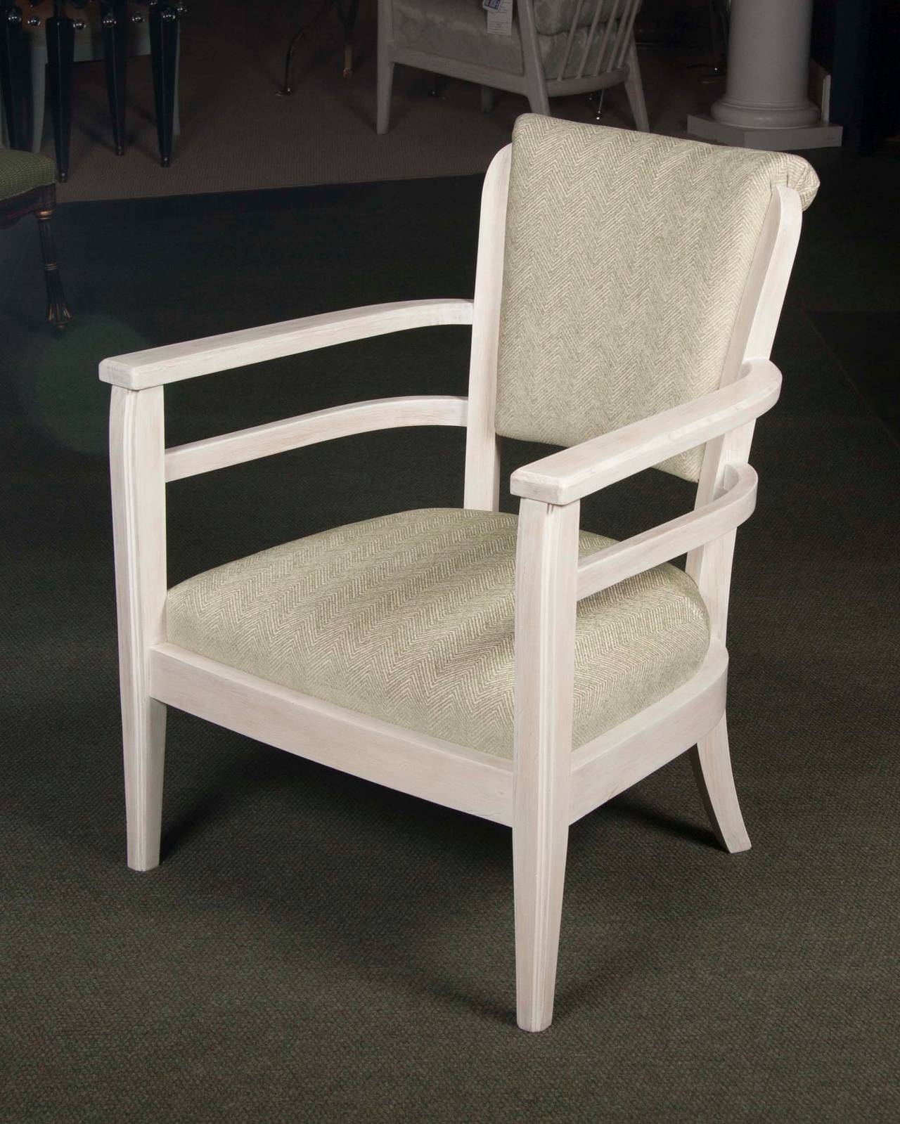 A mid-20th century French armchair of pickled wood with upholstered back and slip seat having open arms and tapered front legs.