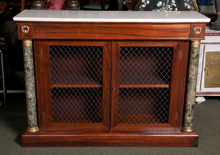 A rosewood regency credenza with bronze grill doors, faux marble scagliola columns and original white marble top.