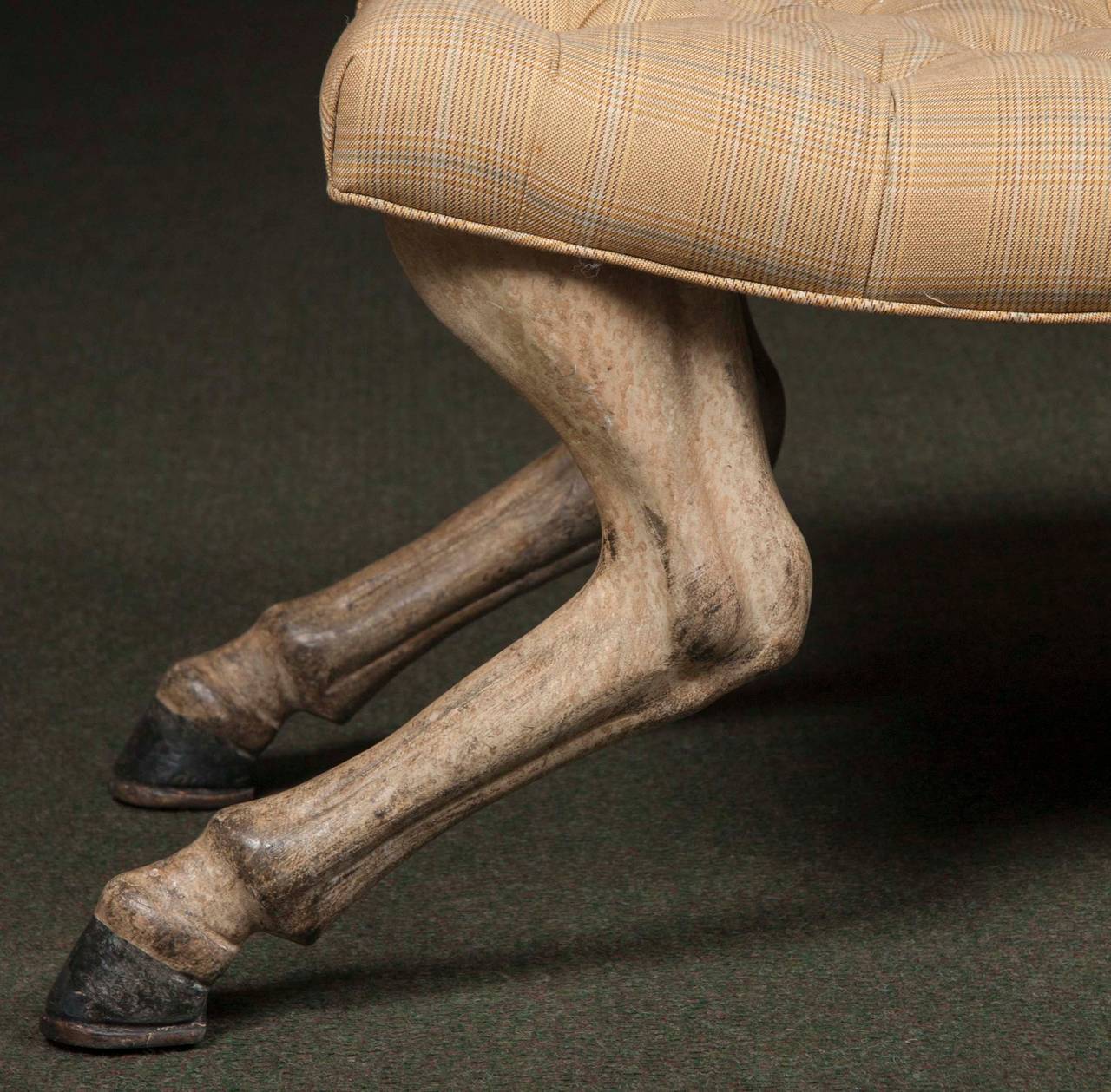 A John Rosselli upholstered tufted stool with carved and painted wooden legs in the form of animal legs with hoof feet.