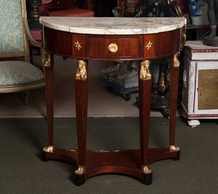 Possibly Baltic or Scandinavian mahogany demilune console with marble top and continental neoclassical ormolu caryatid busts. Ormolu stars added later.