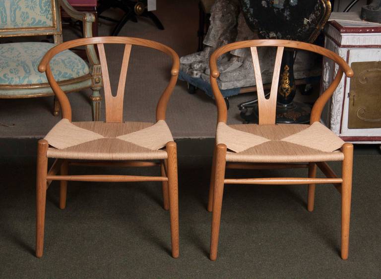 A set of six oak frame wishbone dining chairs designed by Hans Wagner and produced by Carl Hansen.