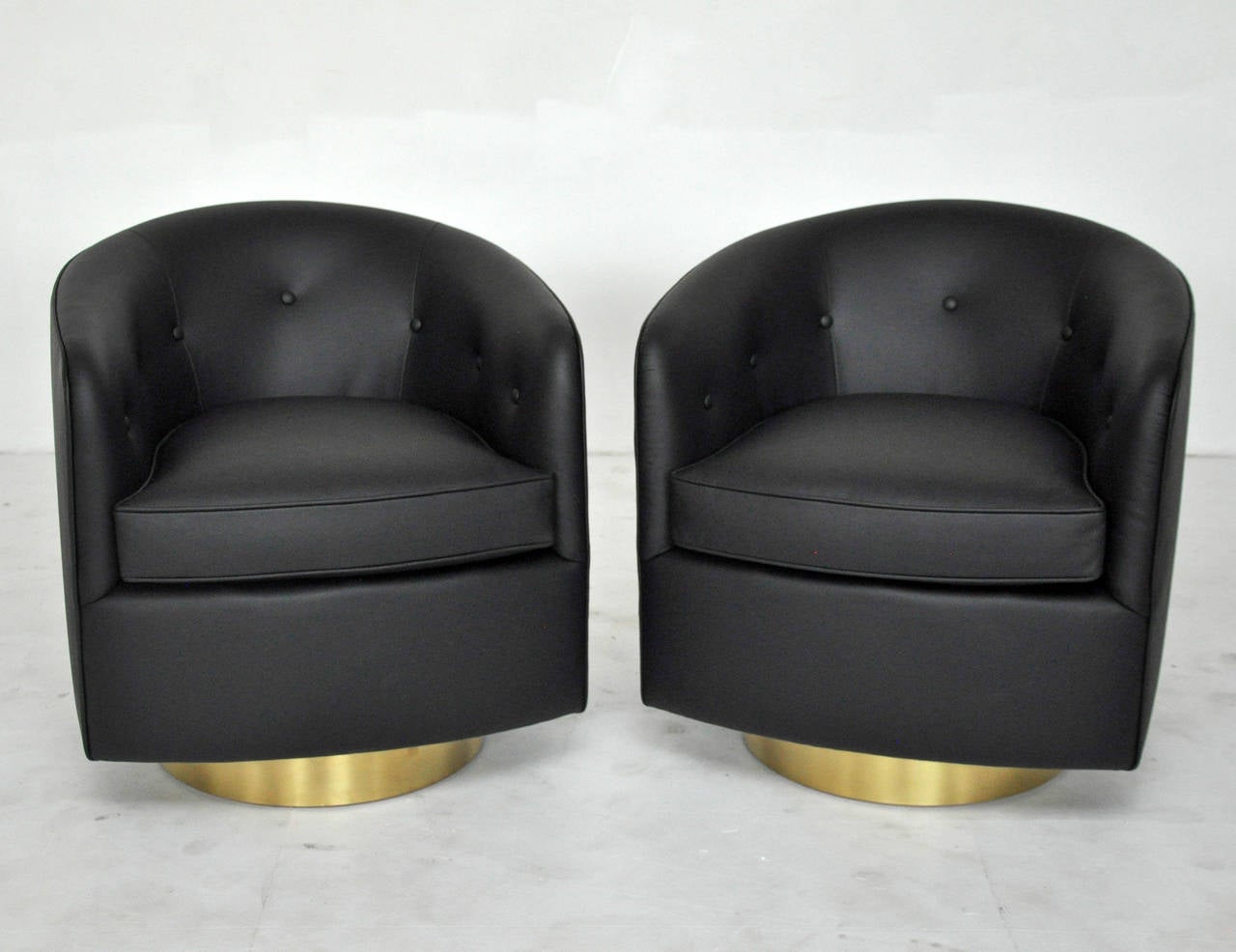Pair of swivel chairs by Milo Baughman. Brass bases with new black leather upholstery. Fully restored.