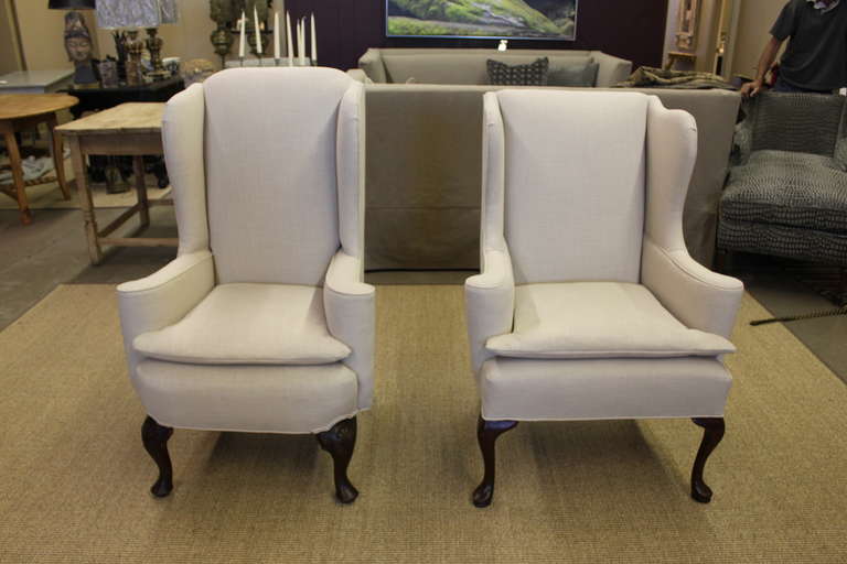 Handsome pair of American Wing chairs with scrolled arms and cabriole legs upholstered in white linen fabric.