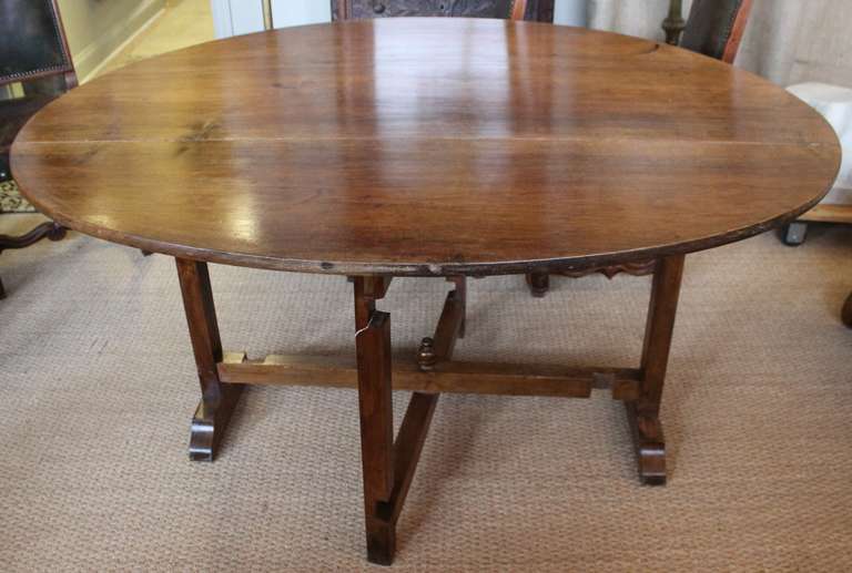 Unique French wine table with oval top. Beautiful color and patina. Maybe cherry or walnut.  Top folds up to store flat.