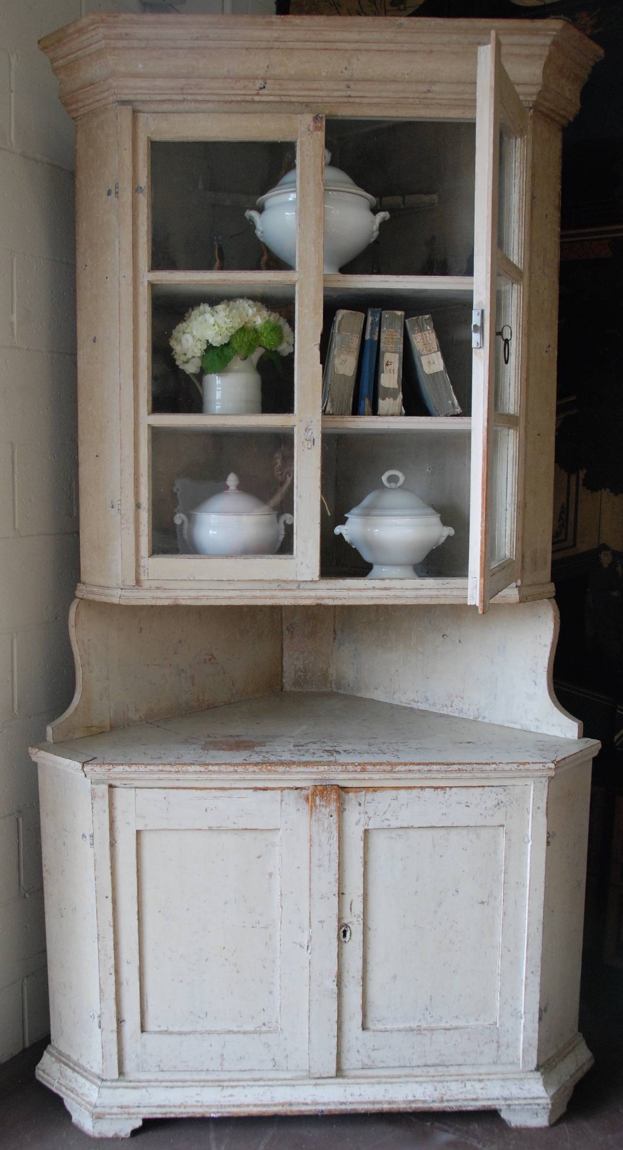 Lovely 18th century Swedish corner cabinet scrapped down to the original cream/white color. Original glass in paneled doors.