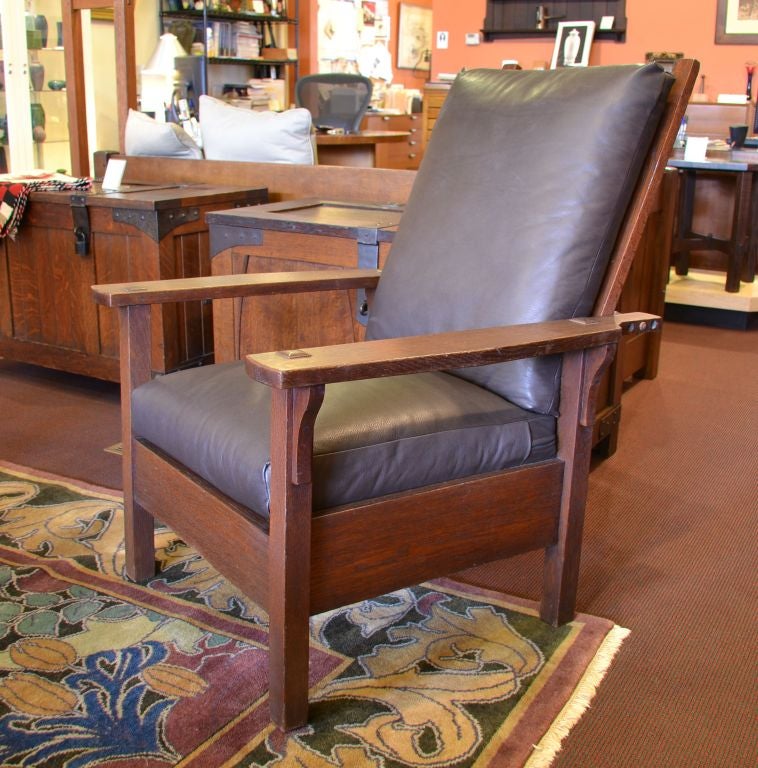 This Gustav Stickley Morris Chair is in excellent condition and has been newly upholstered in high quality dark brown leather. The seat and back are down filled making this quite comfortable. The seat foundation is caned much like how it was