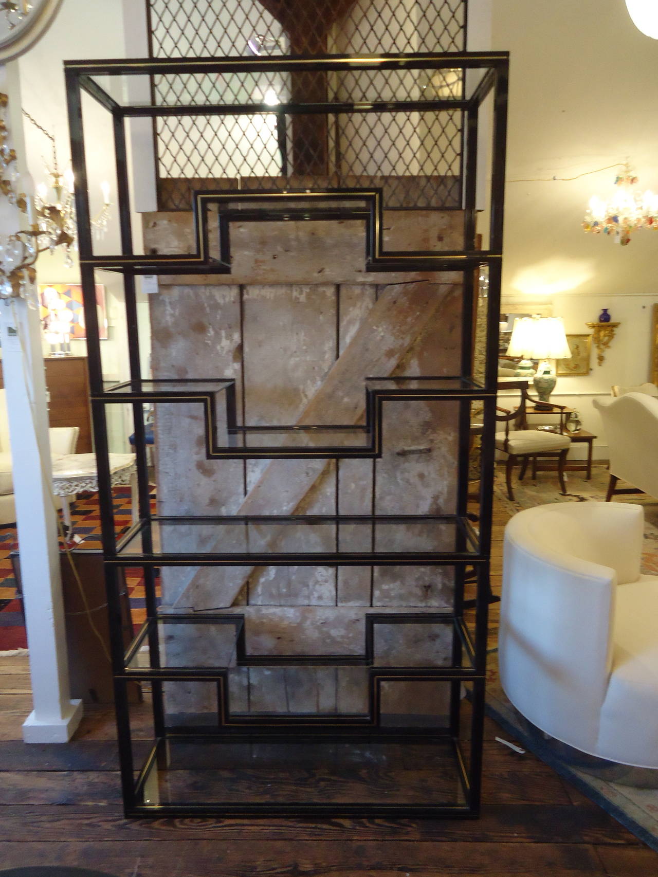 Large sized étagère of shiny black lacquered aluminum with gold foil banding or stripes, schnazzy design with five glass shelves and three smaller stepped shelves that add pizazz to otherwise flat ones. Ample display surfaces, with the chic Pierre