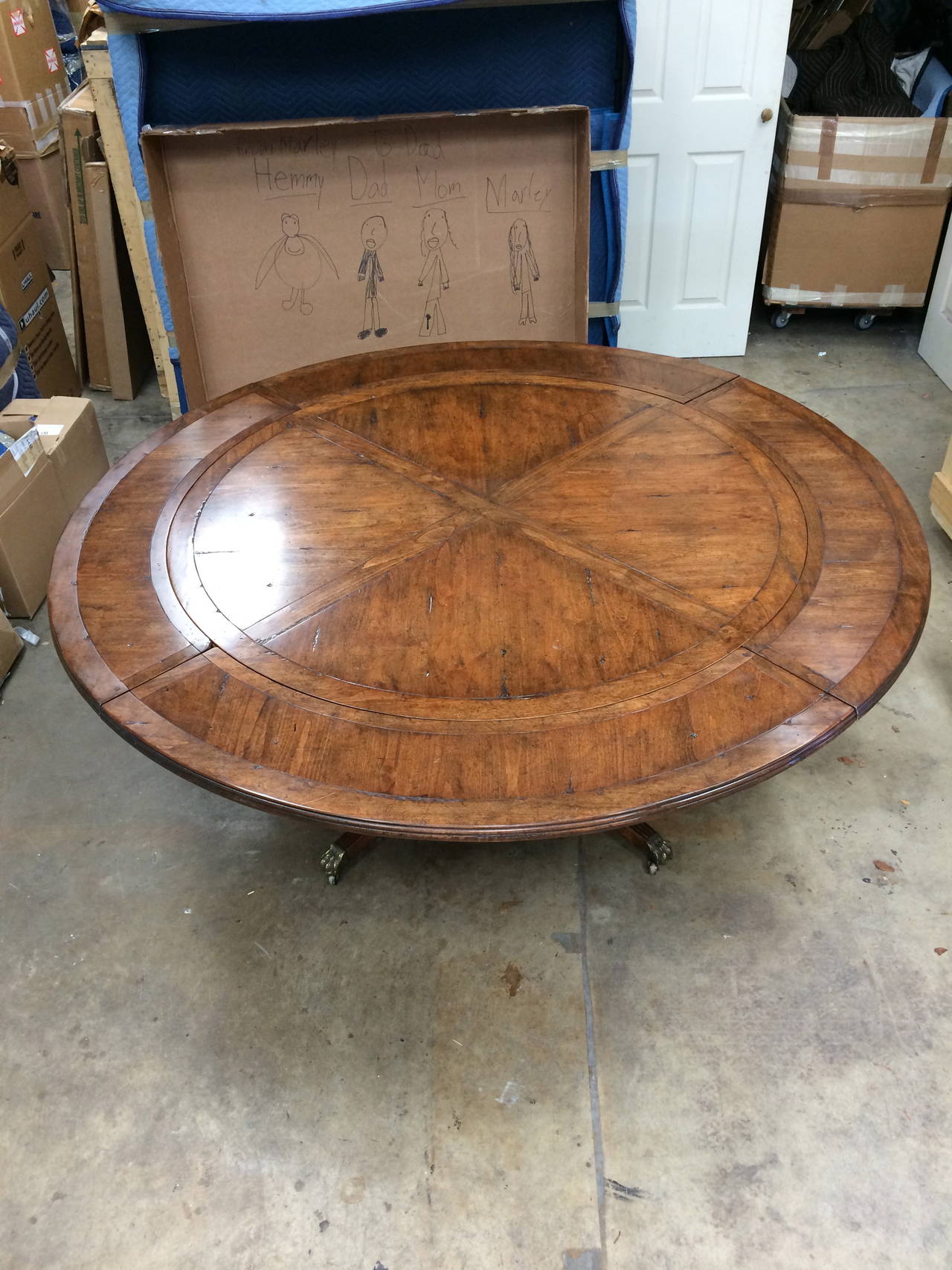 Gorgeous distressed walnut circular plank top over radiating legs with brass paw capped feet on casters. Edge is reeded. Leaves attach to outside periphery of table. Without leaves 53.5 diameter.