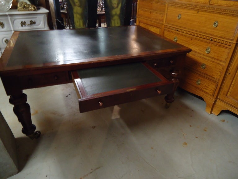 A handsome crotch grain mahogany table with crossbanded veneer, gorgeous and masculine William 4th legs on big brass egg casters; 3 drawers on each side, middle drawer opens to a writing top and has a hidden compartment underneath for storage.
Top