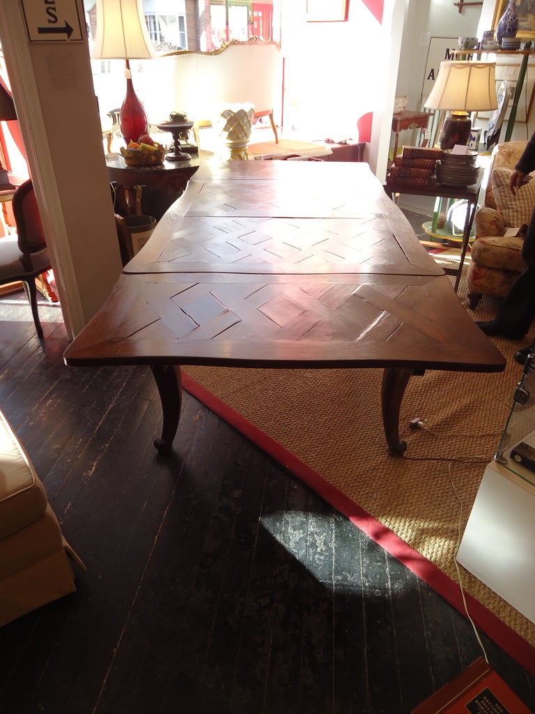Very old, loaded with character and fully functional dining table, a mix of oak and elm with beautiful parquetry on top and carved embellishments on the apron and legs.  Stamped on top of the legs 