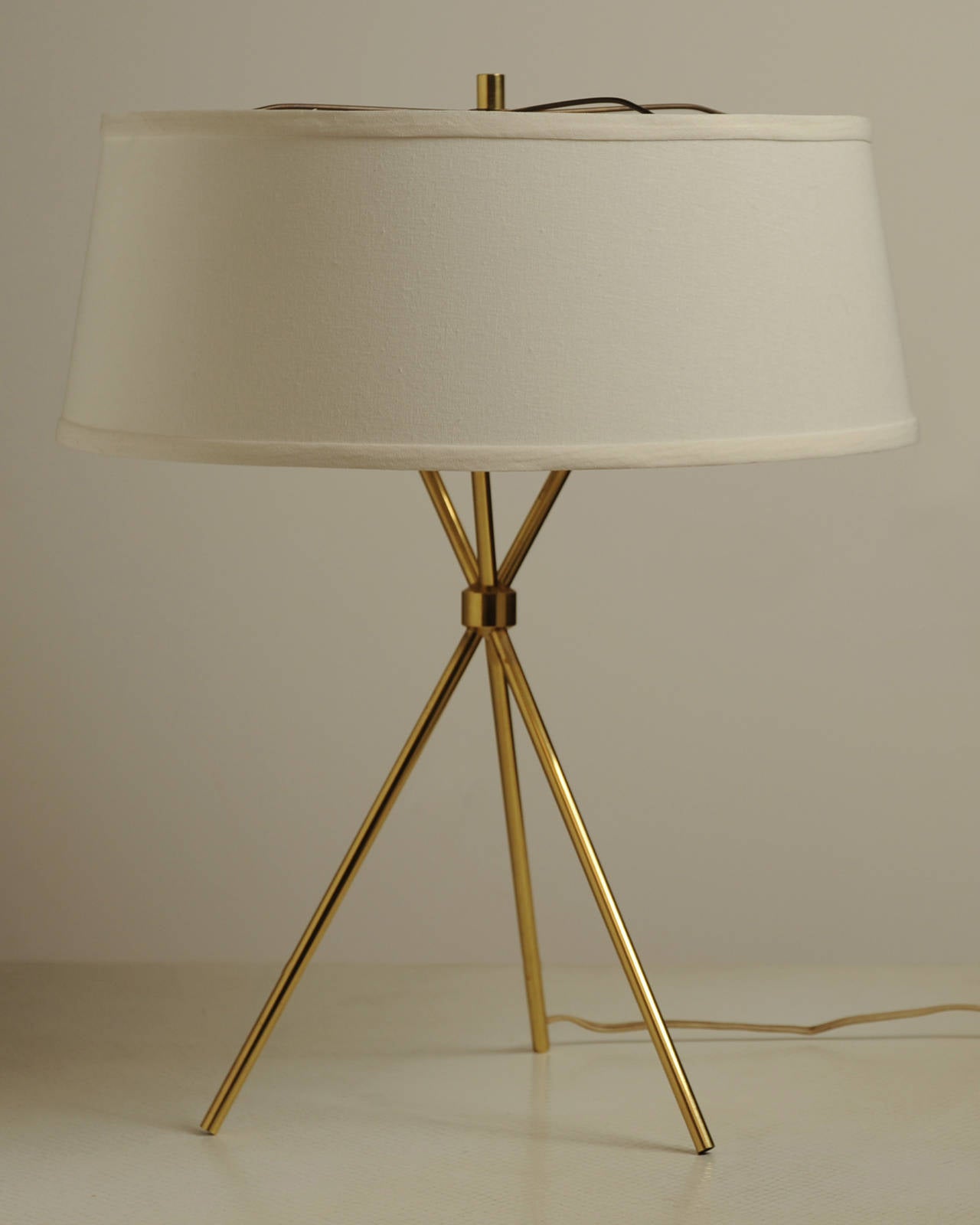Stunning tripod table lamp in a polished brass with original shade. No markings, but style of model no. 170. Robsjohn-Gibbings for Hansen Lighting.
The frame of the original shade has been recovered to match the original fabric; shade is 6 1/2
