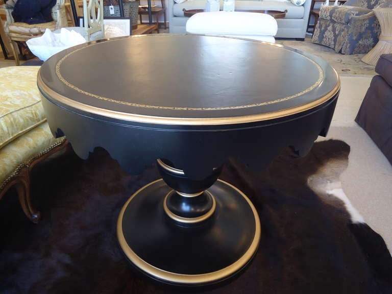 Great size as a sidetable or accent piece.  Terrific Hollywood glamour.  Scalloped periphery, black and gold tooled leather top, ebonized black and gold wood pedestal.