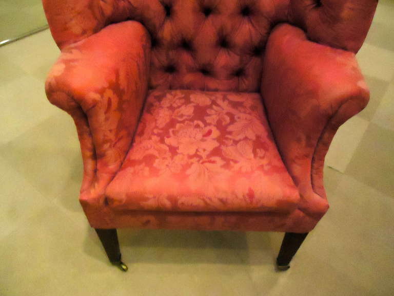 Tall and thin, stately with a high tufted back and an enveloping curve.  Covered in cranberry damask with nailhead detailing.  Rests on shapely mahogany legs capped in brass with small casters.
27.75 W arm to arm
Seat 18.5 D