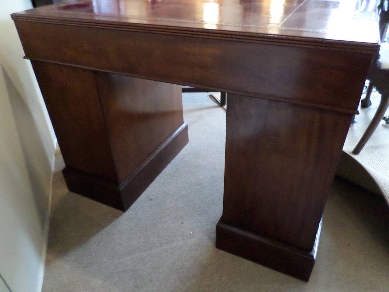 The desk is in three parts, so it is easy to move. The overhanging tooled red leather top has three working drawers and rests on two pedestal bases. The pedestal on the right has a double drawer at the bottom, good for files. Brasses are original