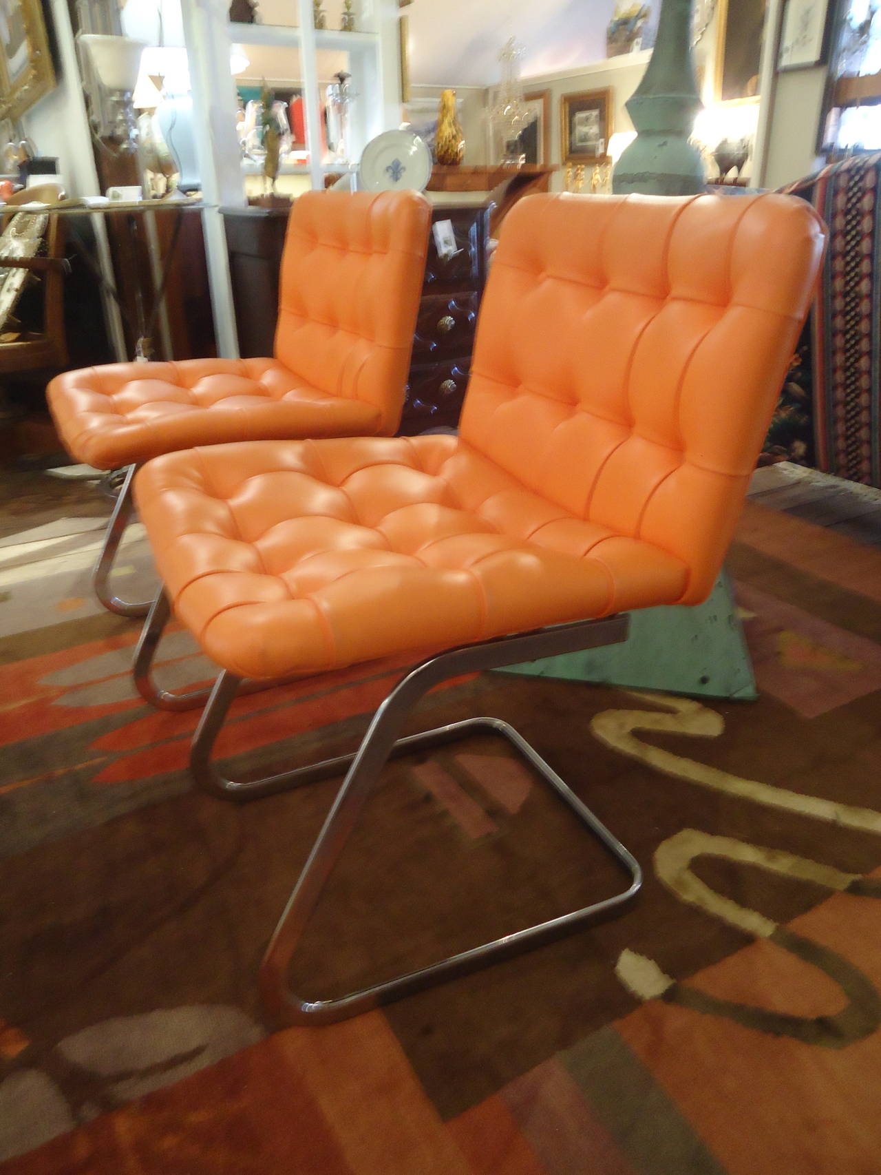 Super cool Stendig armless chairs in a bright orange button tufted faux leather with chrome legs.