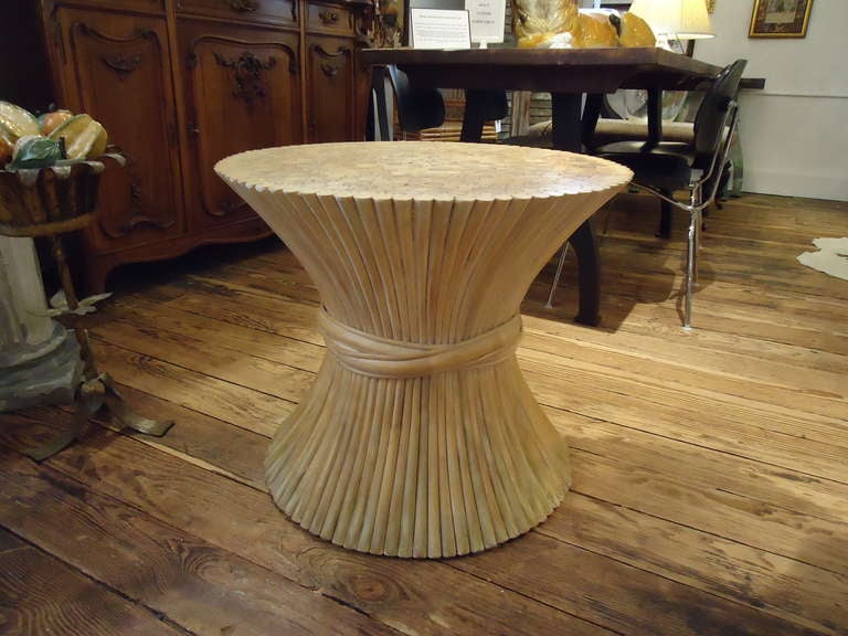 Natural rattan side table in the form of a sheaf of wheat by McGuire.
Currently out of production. The base is handcrafted of Palasan rattan poles that are cinched in the middle by a heavy braid of rattan.  The top surface is a beautiful collection