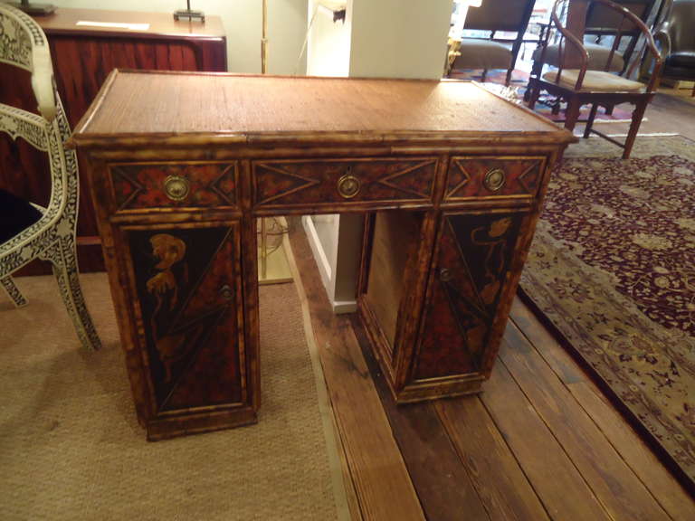 Lovely diminutive bamboo and rattan dressing table or desk.  Gorgeous chinoiserie painted panels.  3 drawers on top level, shelves for storage behind panel doors. Original hardware.