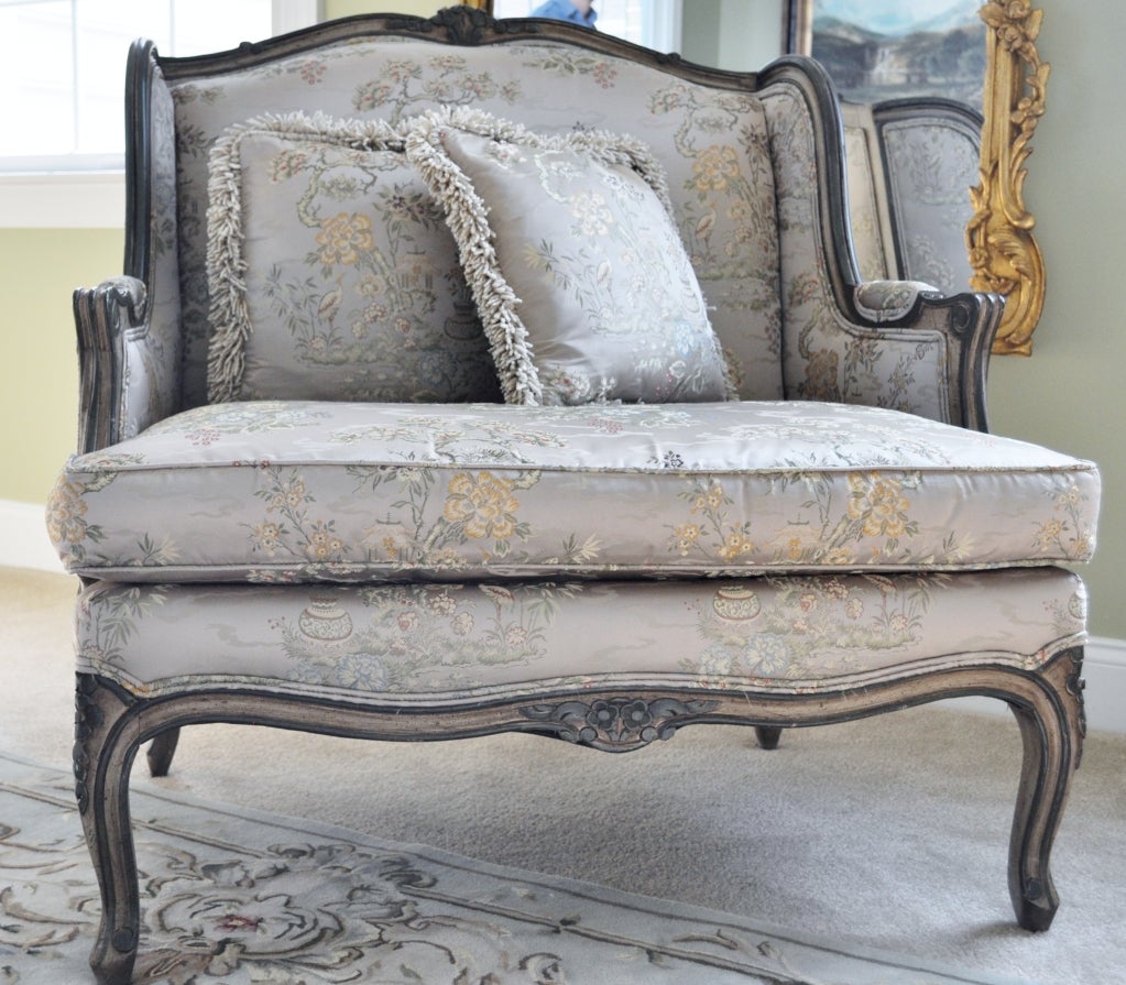 Beautiful carved wing chair and ottoman upholstered in stunning Chinoiserie silk. Two accent fringed pillows included. 
Chair: 31.5 W 27D 35H   Ottoman: 18H 20D 36W