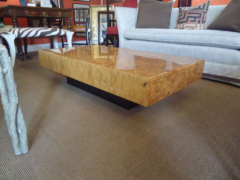 Super slick, low slung, mid-century burl wood coffee table in heavy lacquer. Two recessed drawers, one at each end. Black inset base.