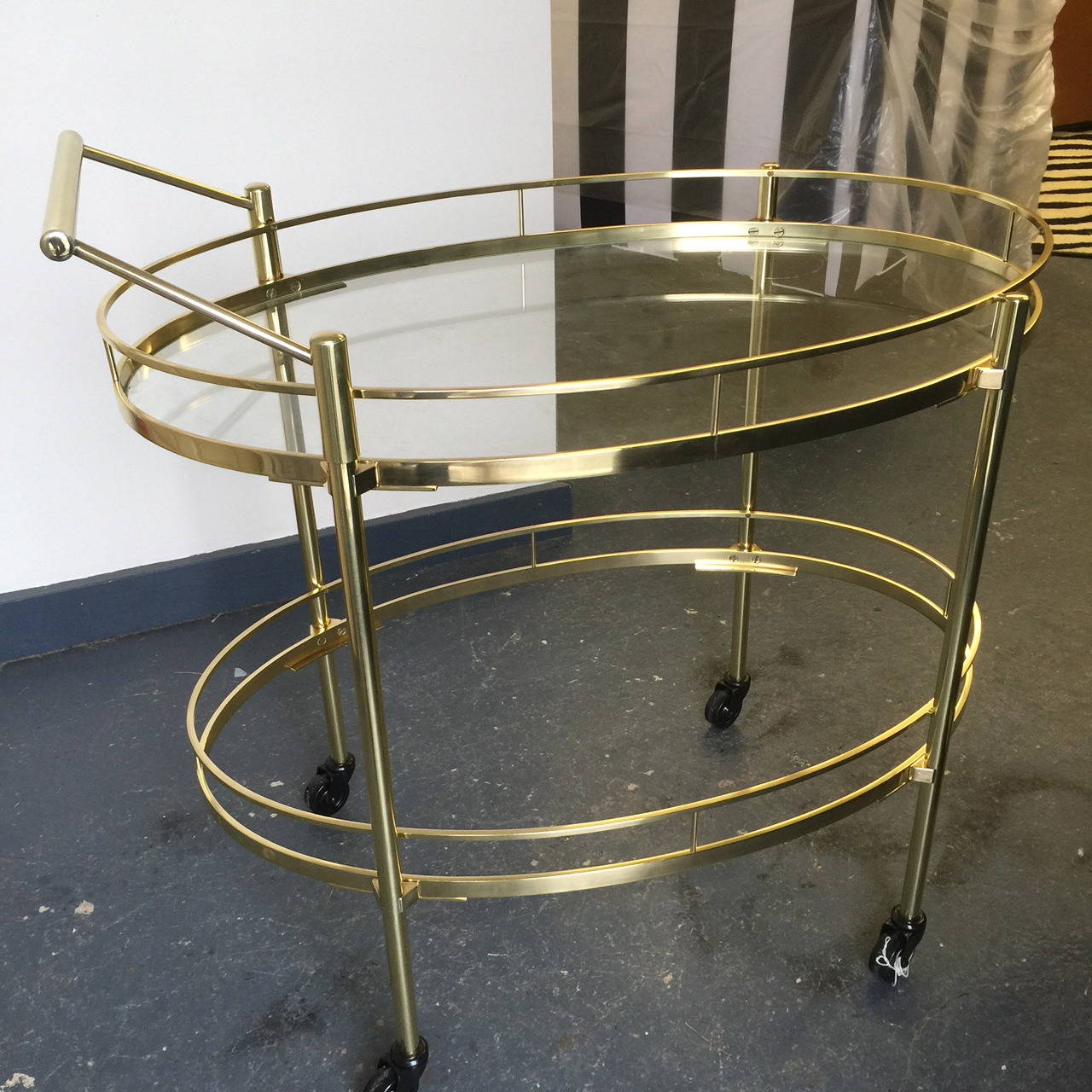 Solid brass bar cart on wheels.  Two oval shaped glass tiers.