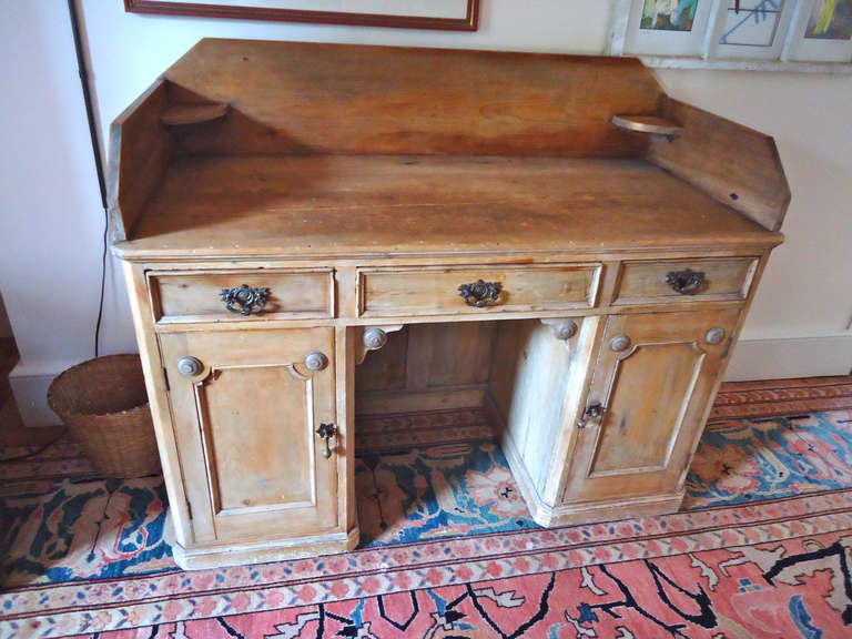 Very handsome large functional desk, rustic unfinished pine. Great storage, outfitted with file cabinets behind the two doors.  Indigenous cracks and distress, part of the charm.  Original brass hardware.
Chair opening is 24