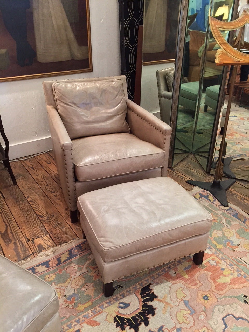 Two very good soft leather club chairs and ottomans in a neutral very pale celery green with brass nailheads and ottomans to match.  Labels say ABC Carpet.
Seat H 18