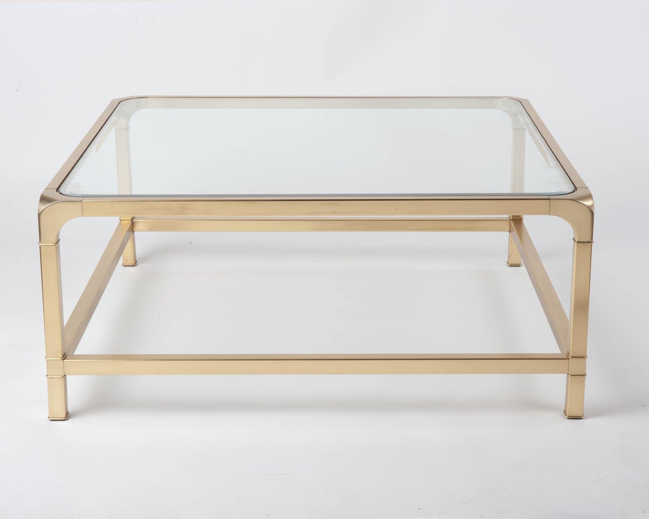 Sleek clean lines, brass and glass square coffee table in the style of Milo Baughman. Beveled glass insert. 
It has been professionally restored and lacquered. Still has some age appropriate pitting, most noticeably inside where the glass sits.