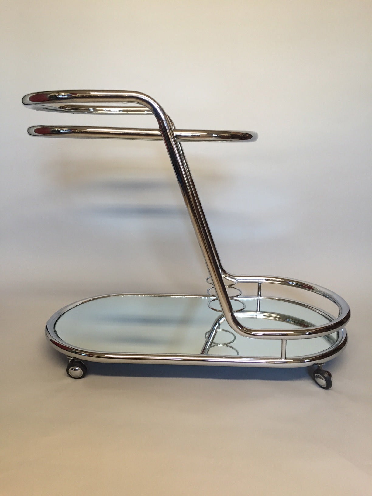 Very stylish shiny chrome, glass and mirrored bar cart having two oval shaped tiers, wine rack and an Art Deco feel.