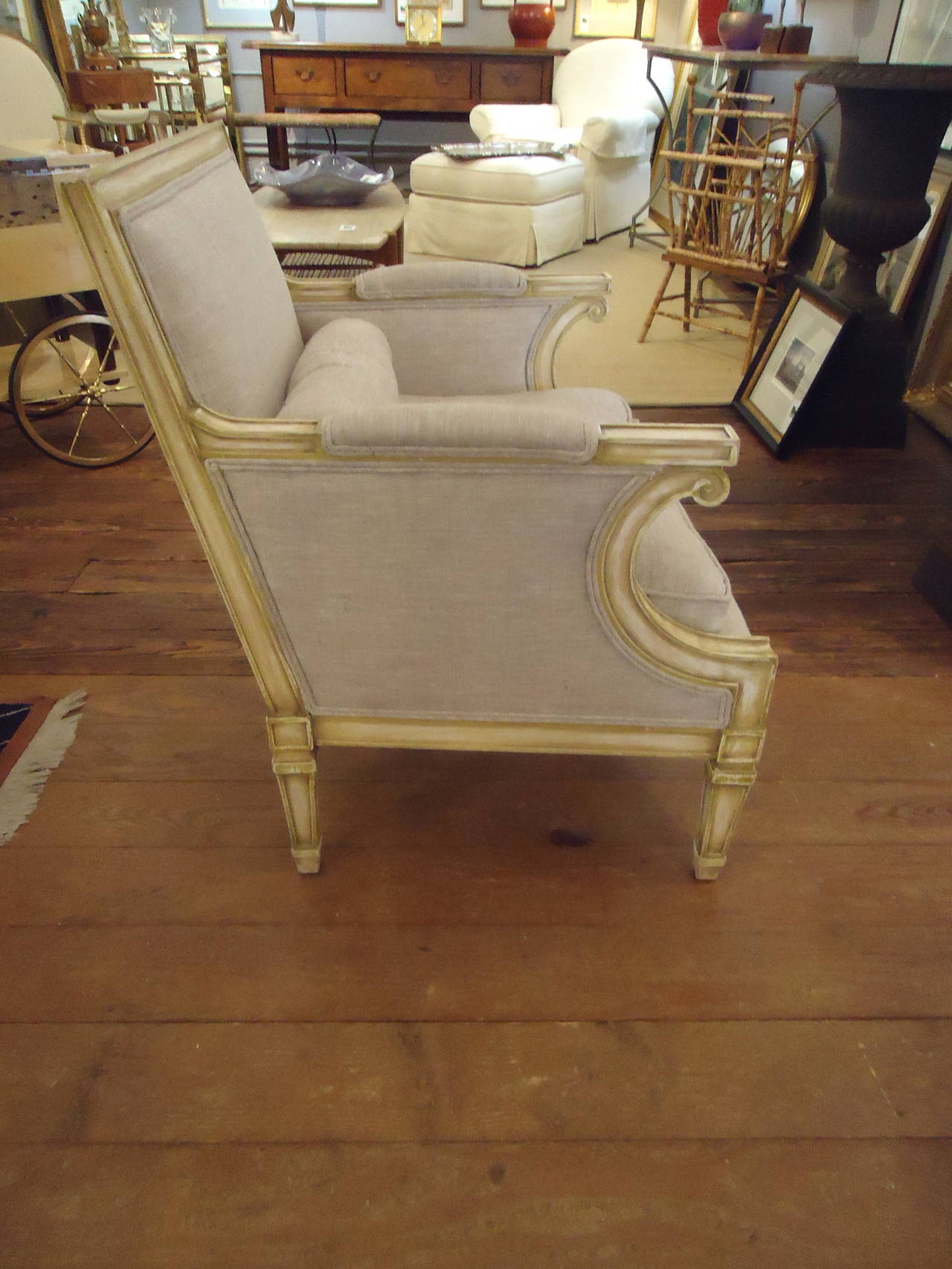 Roomy and comfortable French style chairs having a painted antiqued off white wash on the wood frame,  and neutral sand colored upholstery.  Seat cushion is down.