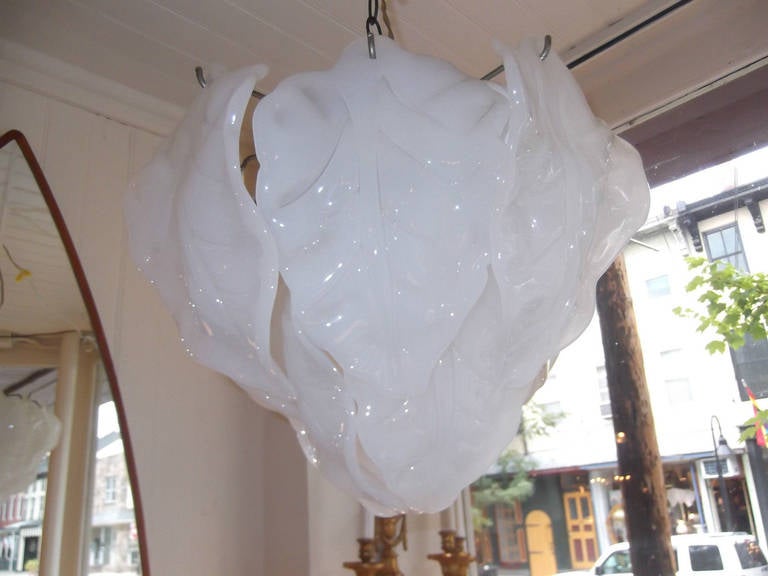Lovely chandelier with Italian Murano glass in the form of leaves hanging from a chrome armature.
Has the Camer label, made in Italy.
The handmade leaves are a slightly opalescent translucent glass.
When lit glows white.