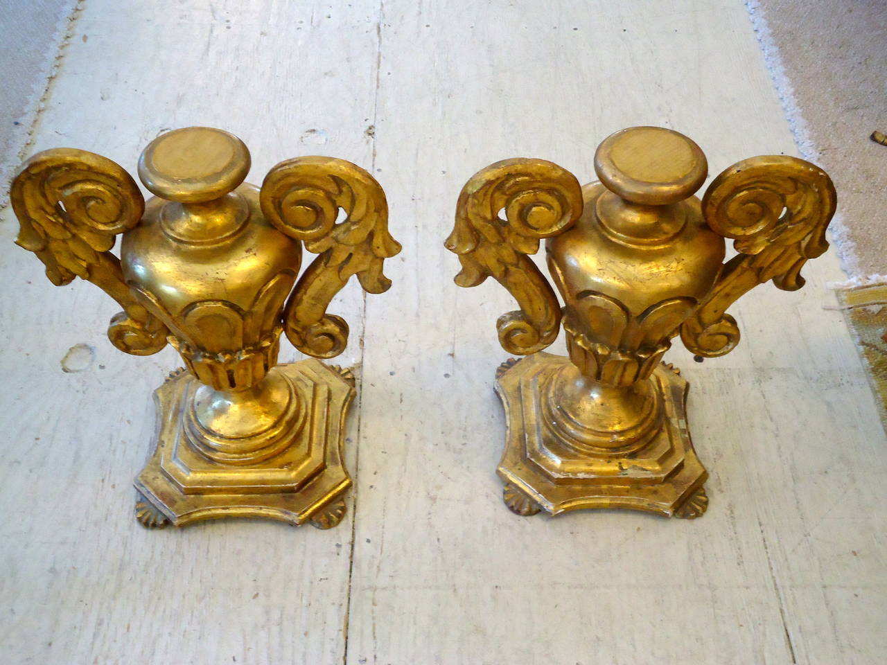 Two symmetrical and dramatic gold leafed, carved wood, urn shaped objects sitting on feet. Made in Italy. Tony Duquette flair!