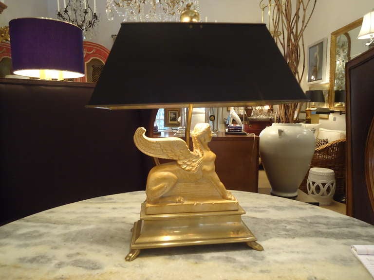 Very handsome lamp, sphinx like figure in carved wood or possibly composite, rests on brass base with four feet.
Shade is bouillette style, all brass and black laquer on the outside.  Shade measures 15