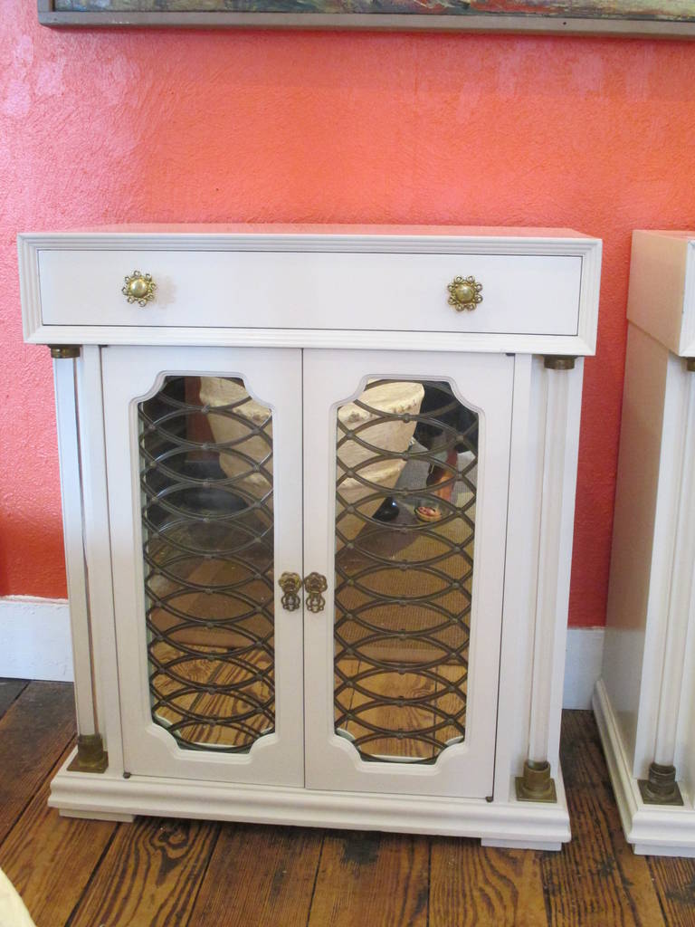 Two mid century Regency Style cabinets with Lucite Columns on the front.  Mirrored panelled doors with handsome brass grating, original decorative brass hardware.  Each night stand has a drawer as well.