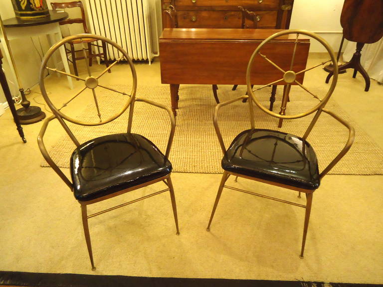Very unusual chic armchairs made of hand-forged brass in a neoclassical design. Backs are round with spoke like arrows. Seats are black patent leather and easily reupholstered.