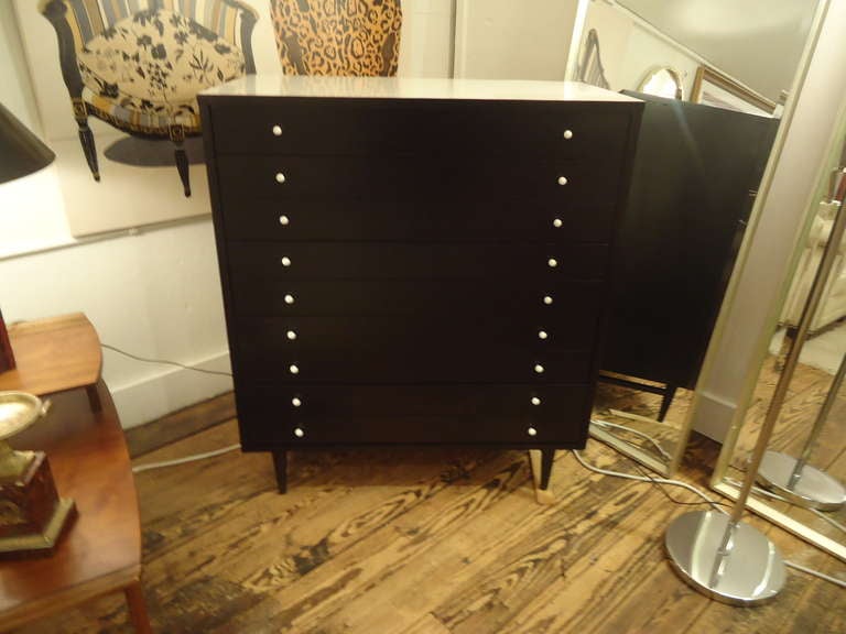 Part of a set which includes night tables and a low bureau with mirror; sleek black lacquer with white lacquer top and small knobs.
Many narrow drawers on top of four tapered legs.