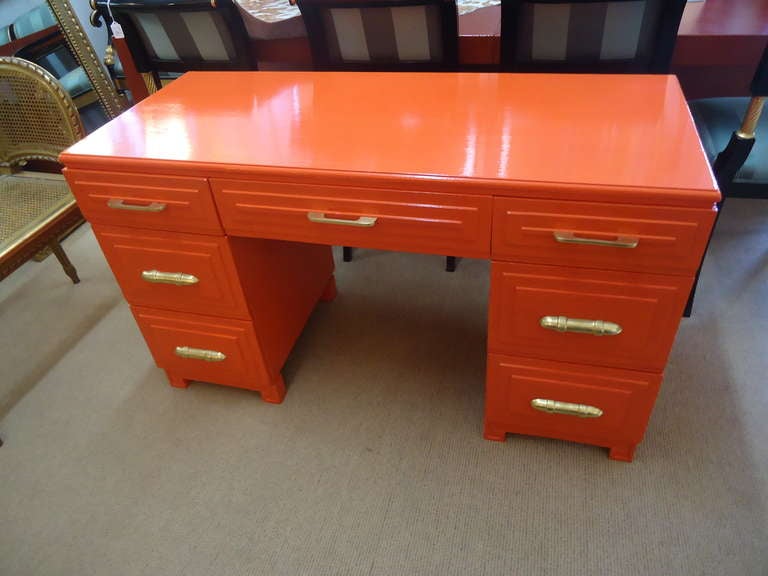 Vintage wooden desk with wonderful Greek key details on the base and beautiful gold/brass hardware, newly laquered in a striking orange. 3 drawers on each side, one in the middle.