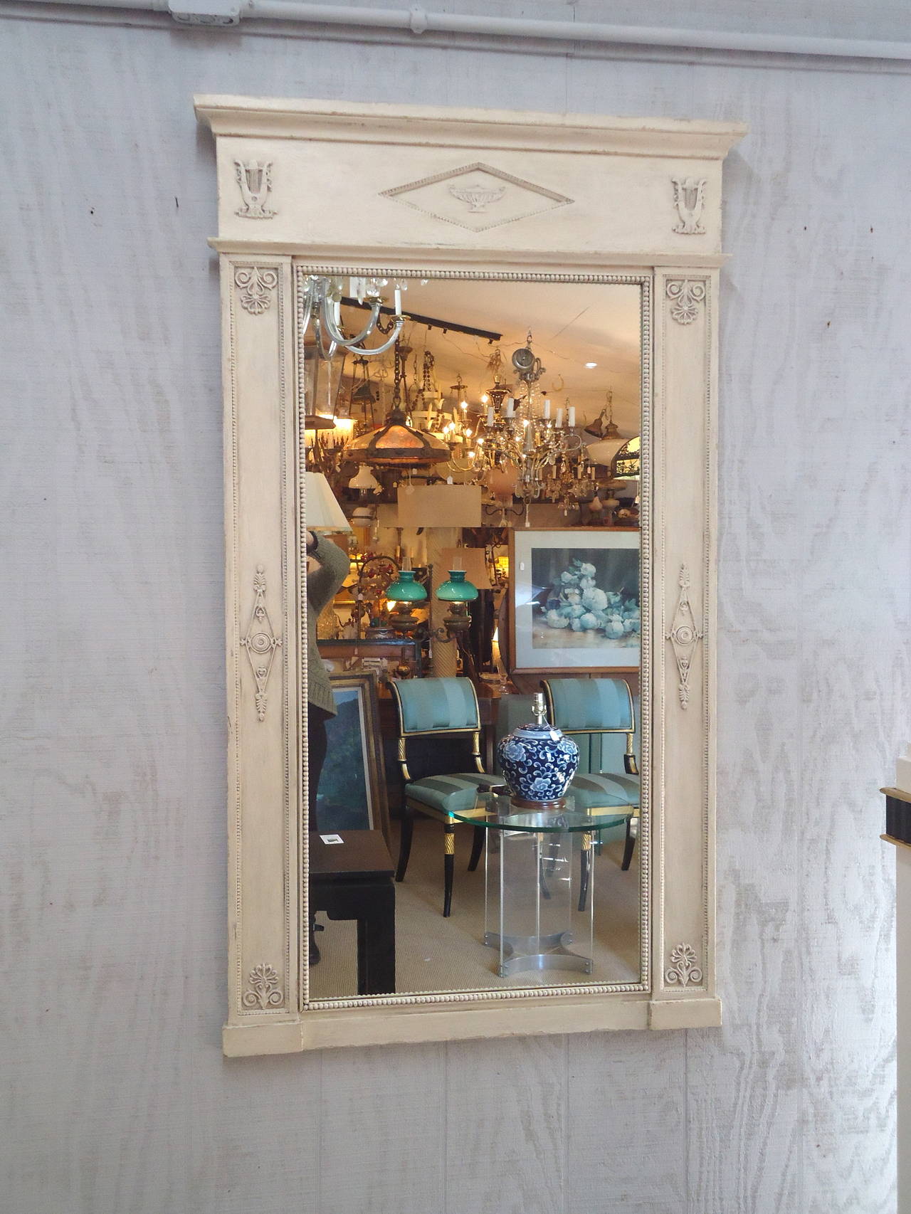 Creamy grey white finish painted wood with lovely neoclassical adornments.  Aged mirror in two pieces, as is customary with this style of mirror.
Body of mirror is 31.5 w