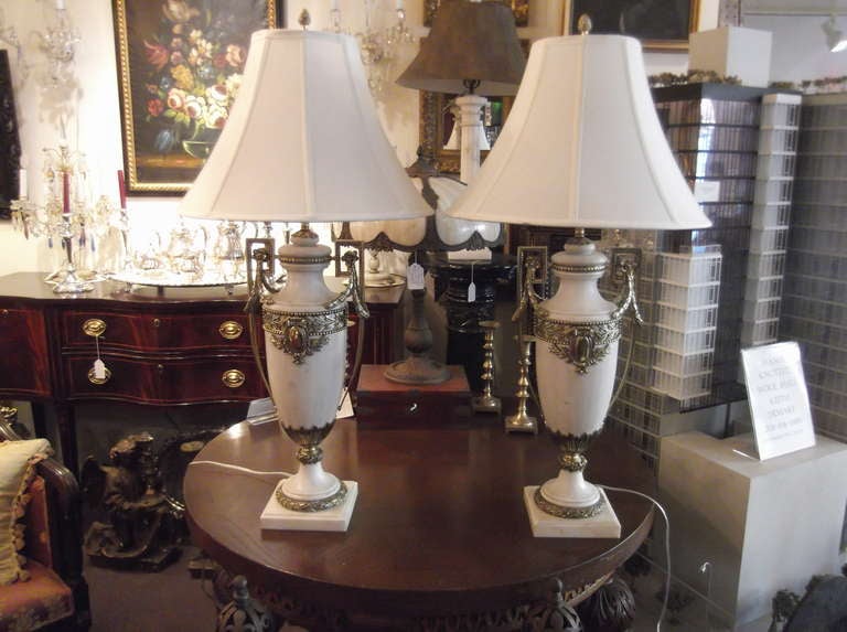 French antique marble urns now electrified with beautiful polished bronze mounts.  Heavy and solid, ivory white marble with intricate bronze handles with olive leaf swags and beaded edge decoration.
In the neo classic style, newly rewired
22