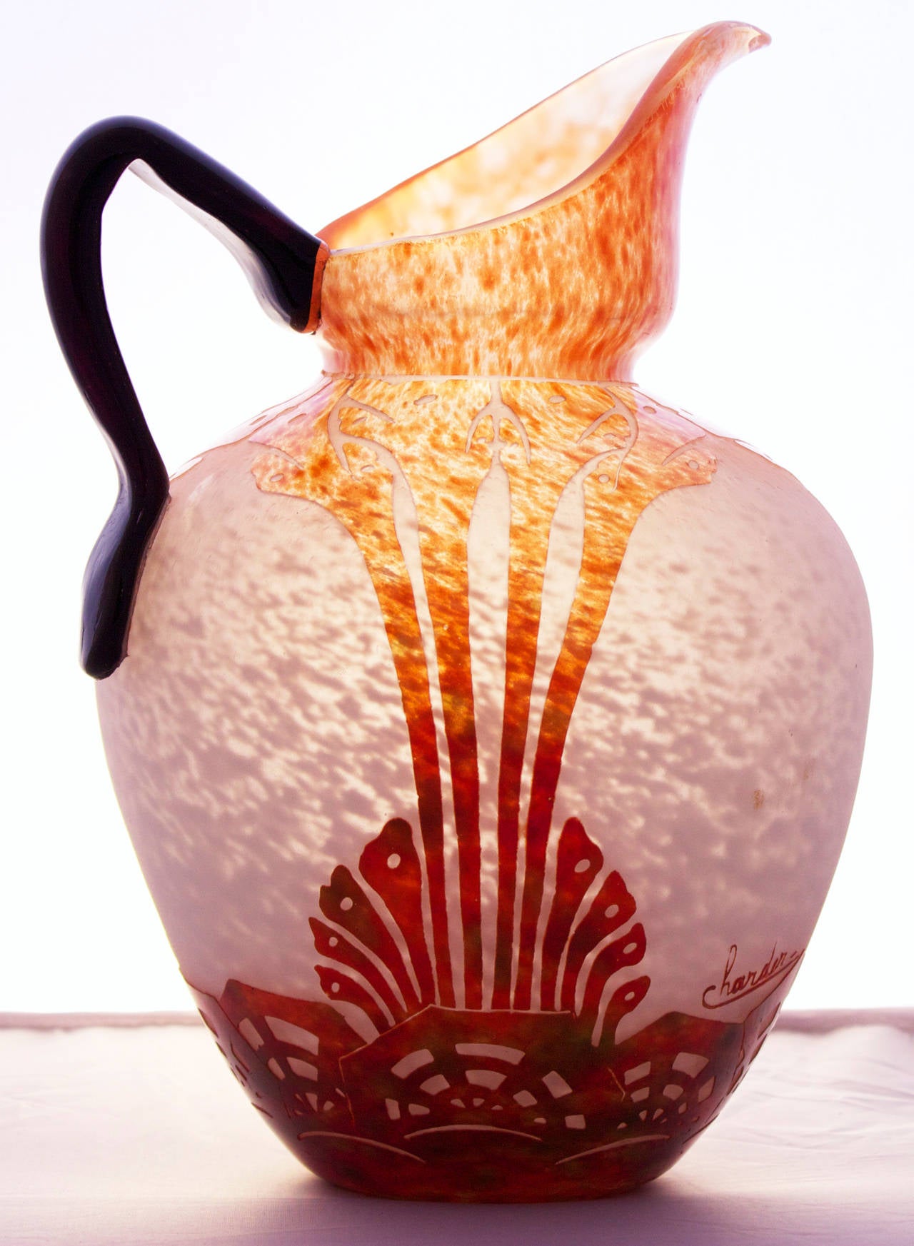 A spiritual son of Emile Galle, Charles Schneider (1882-1953) was a magician with light and helped raising the art of glassmaking to ever higher levels.
This glass pitcher shows a cutted geometric pattern in a graduation from bright orange to deep