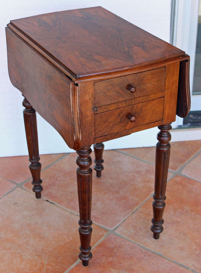 This classical walnut drop-leaf table has two useful purpose. One side is a work table with three drawers, including a sliding one for knitting and crochet storage. The other side is a night table with a space behind the door having a marble base to