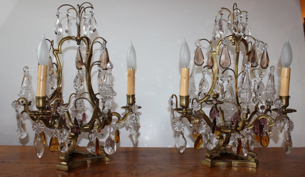 Pair of French tabletop chandeliers in Louis XV bird’s cage style. The crystal pendants are all hand cut and polished and are in four shades, clear, Smokey Topaz, Amethist and Amber.
US Elec.