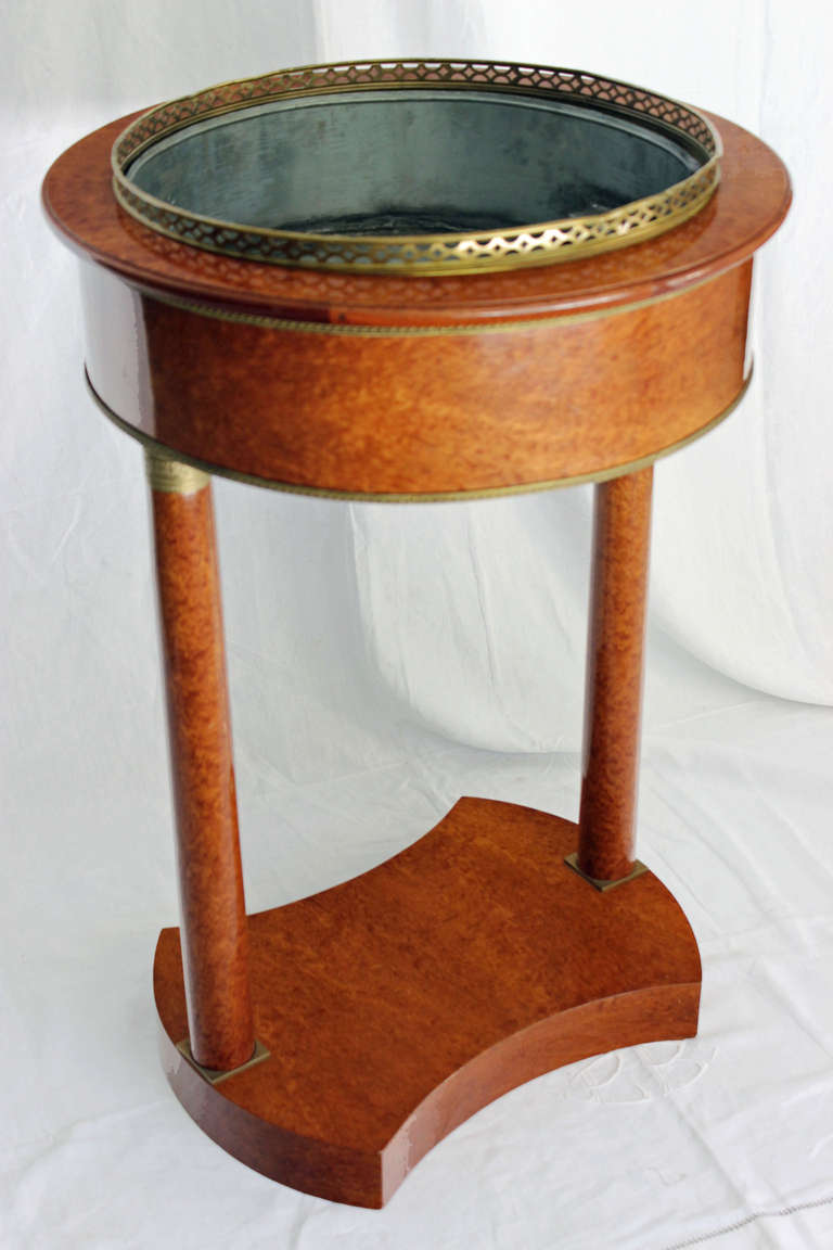 Rare and gorgeous jardinière in bird's-eye maple veneer standing on two feet resting on a base and having gilded brass decor top and bottom.
The top shows a brass 