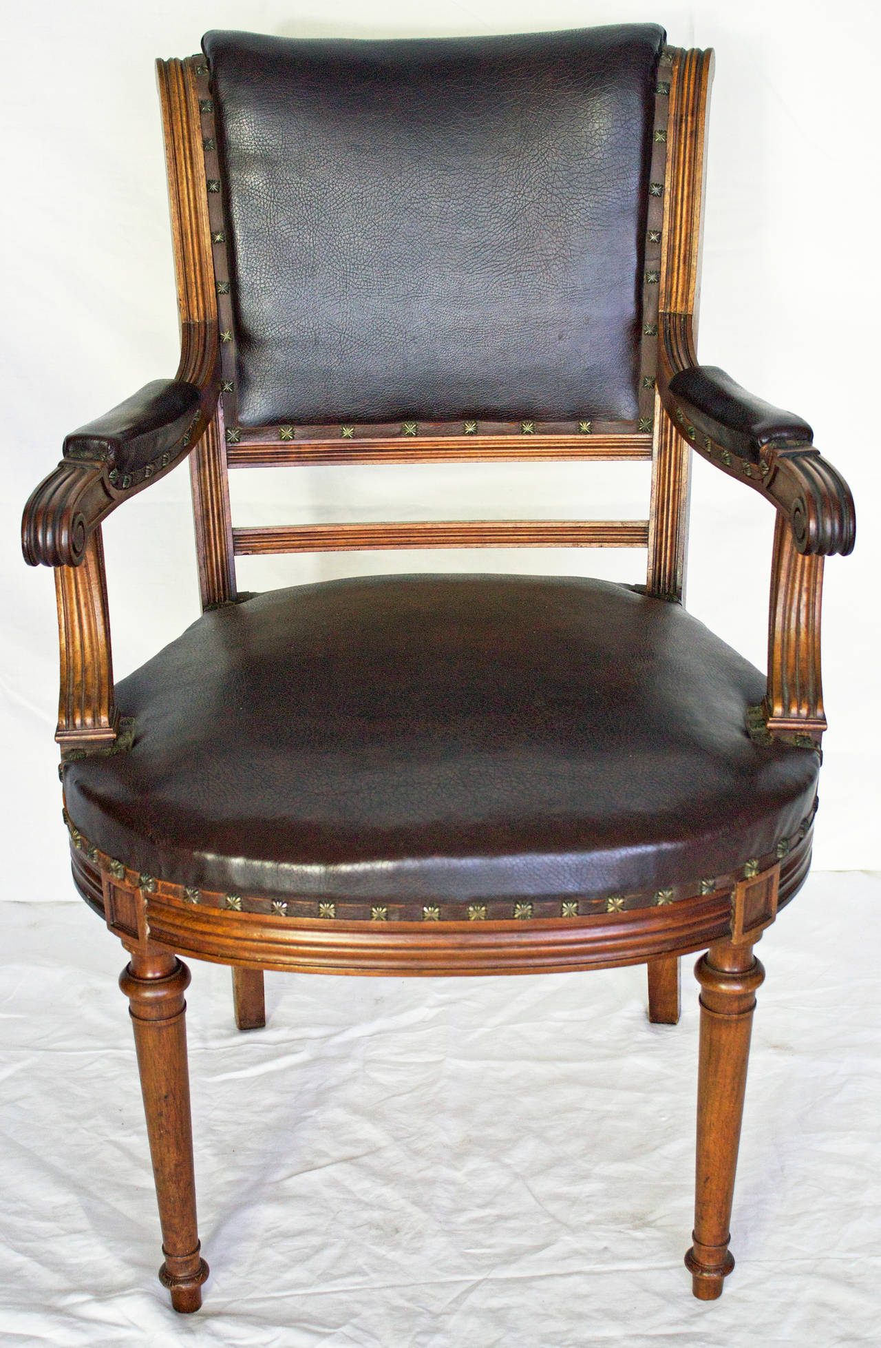 Handsome and comfortable desk armchair in walnut done by the end of 19th century in a Louis XVI style with its fluted woodwork on backrest, armrests, their supports and the seat crosspiece. Light saber shape for the back legs when the front legs are