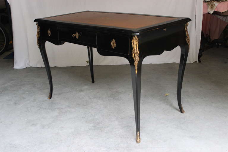 French Bureau plat in black lacquered wood opening by three drawers and two writing slides on its sides.Top rests on four arched feet terminated by bronze dore sabots. Decorated also with bronze dore escutcheons and leaf work chutes.
Beautiful  and