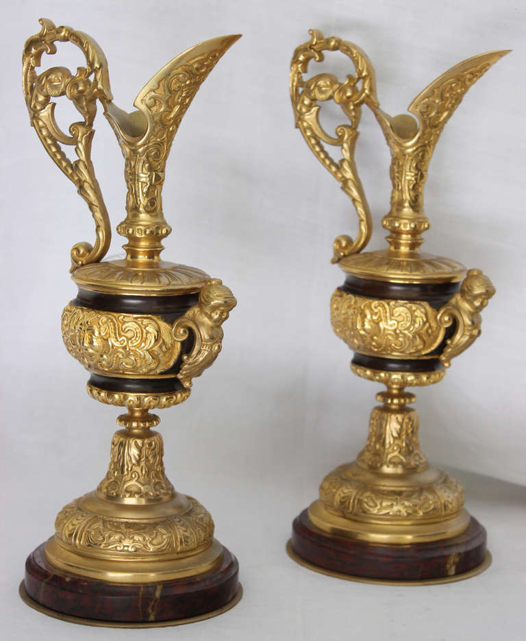 Gorgeous gilding of this Napoleon III period ewers which are engraved with arabesques and lambrequins. Each has its neck wide mounted with a faun head applique and an openwork of foliage and stylized dolphin head handle.
The base is a 