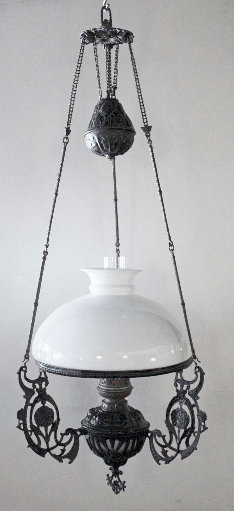 Charming hanging oil Lamp with a black lacquered bronze frame surmounted by a white opaline glass shade..The oil reservoir is also made of a white opale glass inserted in a black bronze structure..
The wick is surrounded by a cylindrical crystal