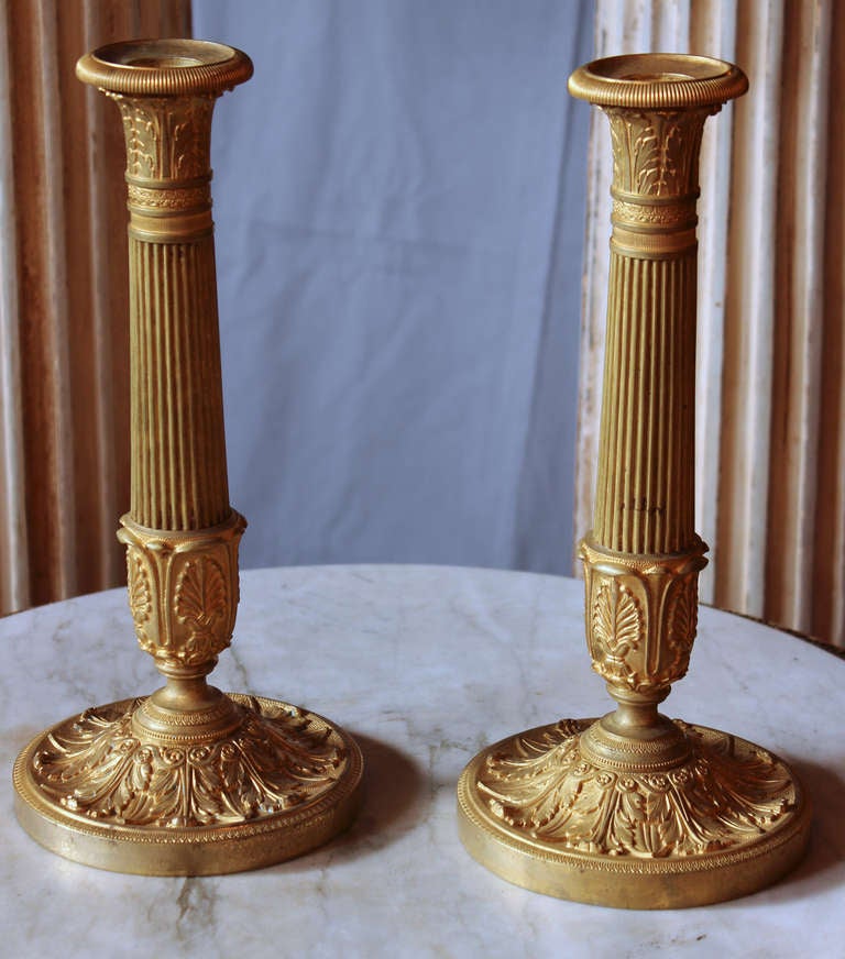 Wonderful pair of doré bronze candlesticks, each having a slightly fluted stem and finely engraved decor of acanthus leaves on base and palmettes on top and bottom of the stem.
 