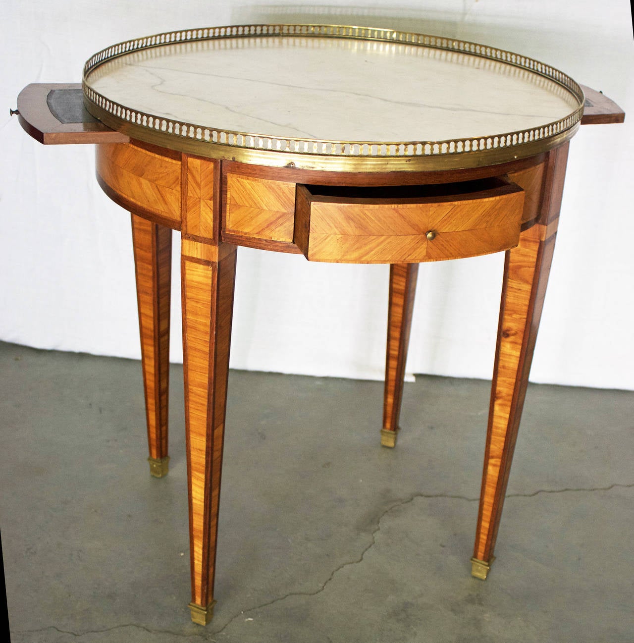 Très élégante et décorative table Bouillotte de style Louis XVI avec placages de bois de rose et de bois de roi sur le tablier et les pieds. Il comporte deux tiroirs et deux glissières doublées de cuir au-dessus de quatre pieds carrés et effilés