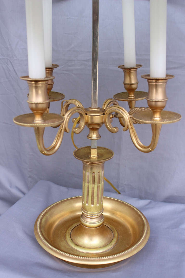 A remarkable doré bronze bouillotte lamp with its original gilding. It holds four light candles which height can be easily adjusted on the central column. The lacquered 